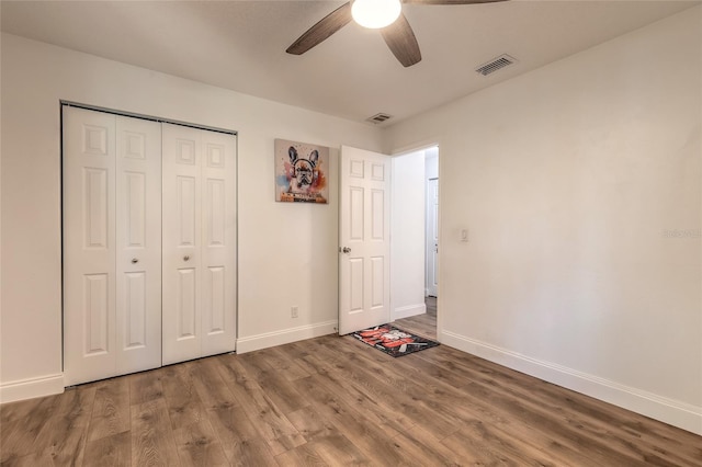 unfurnished bedroom with wood-type flooring, a closet, and ceiling fan