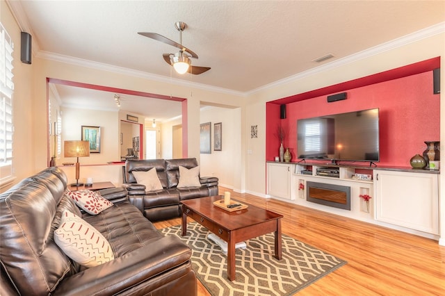 living room featuring a textured ceiling, ornamental molding, light hardwood / wood-style floors, and ceiling fan