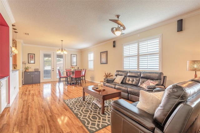 living room with crown molding, a chandelier, a textured ceiling, and light hardwood / wood-style flooring