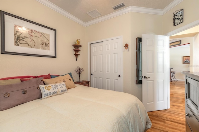 bedroom with crown molding, light hardwood / wood-style flooring, and a closet