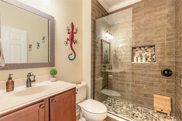 bathroom featuring vanity, ornamental molding, tiled shower, and toilet