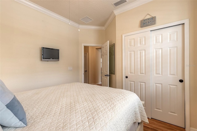 bedroom featuring hardwood / wood-style flooring, crown molding, a textured ceiling, and a closet