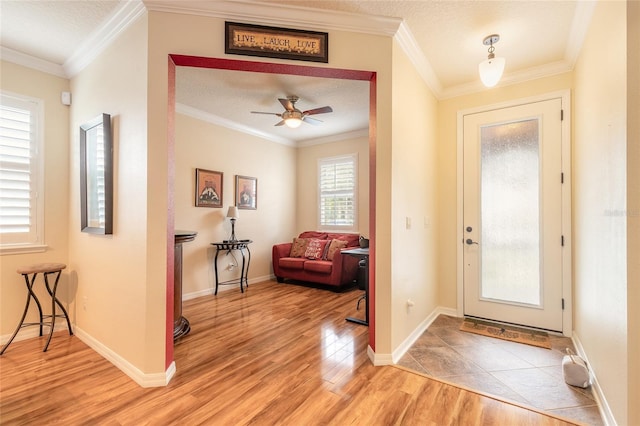 entryway featuring crown molding, ceiling fan, wood-type flooring, and a textured ceiling