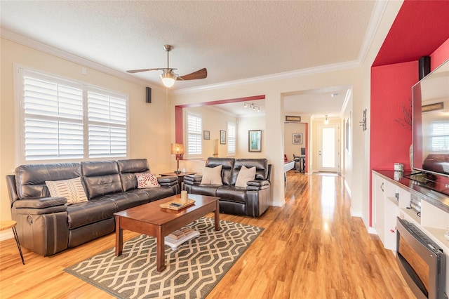 living room with ceiling fan, hardwood / wood-style flooring, ornamental molding, and a textured ceiling