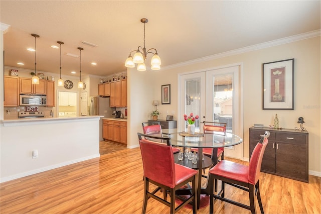 dining space with crown molding, an inviting chandelier, light hardwood / wood-style floors, and french doors