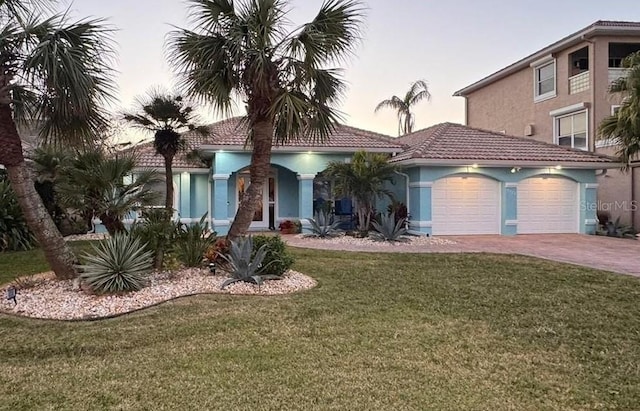 mediterranean / spanish home with a garage and a lawn