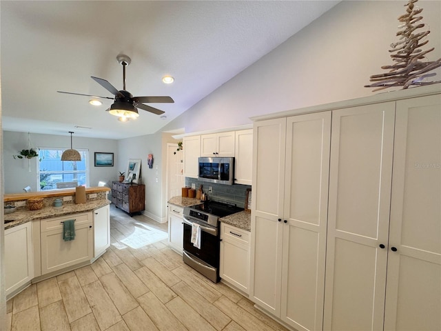 kitchen featuring stainless steel appliances, vaulted ceiling, white cabinets, and light stone counters