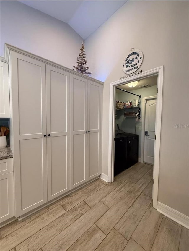 hallway with lofted ceiling and light wood-type flooring