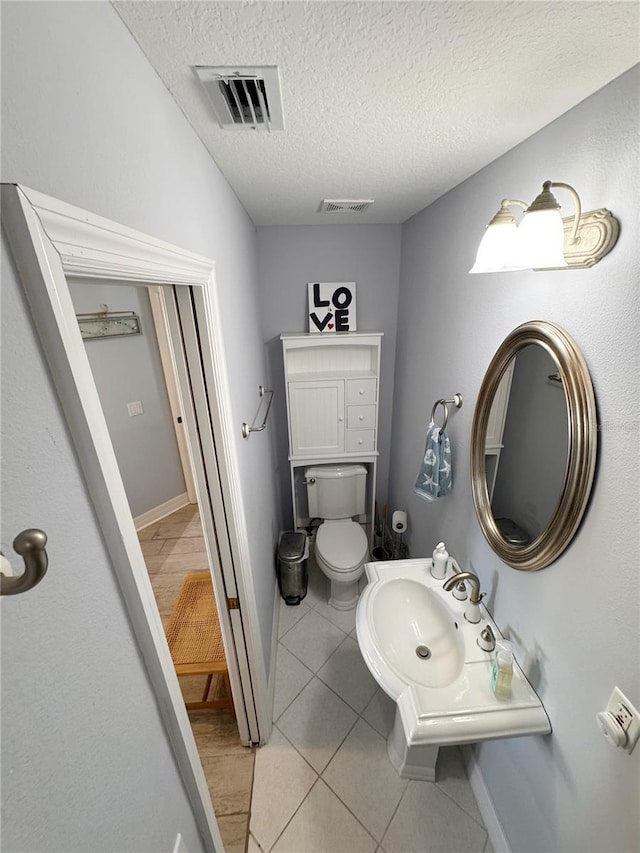 bathroom with tile patterned floors, toilet, and a textured ceiling