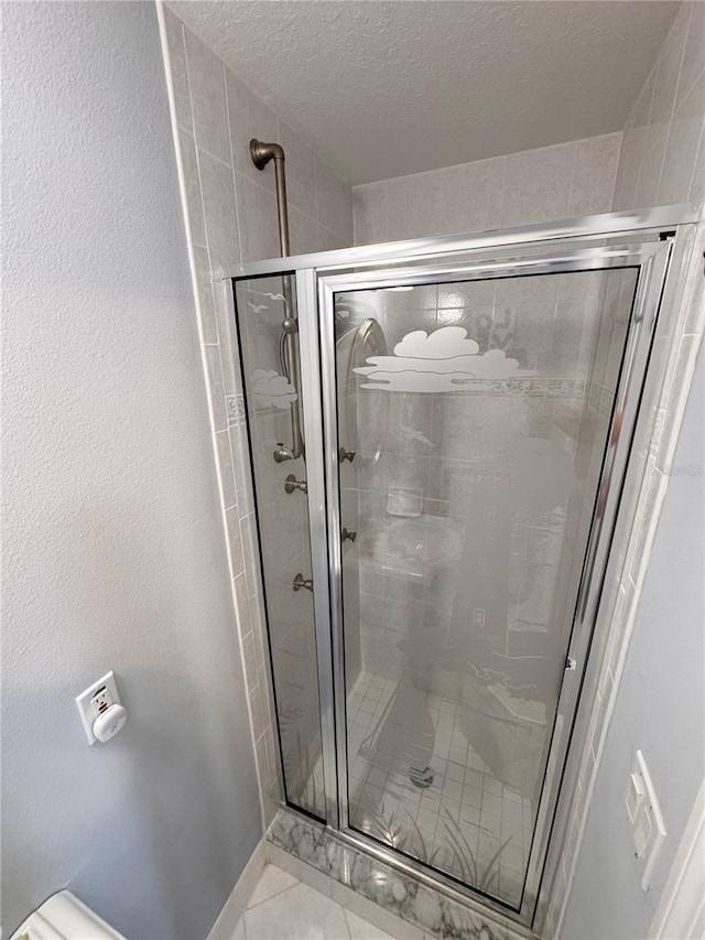 bathroom with a shower with shower door, tile patterned floors, and a textured ceiling