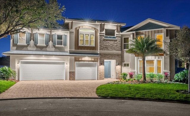 view of front of house with an attached garage, stone siding, decorative driveway, and stucco siding