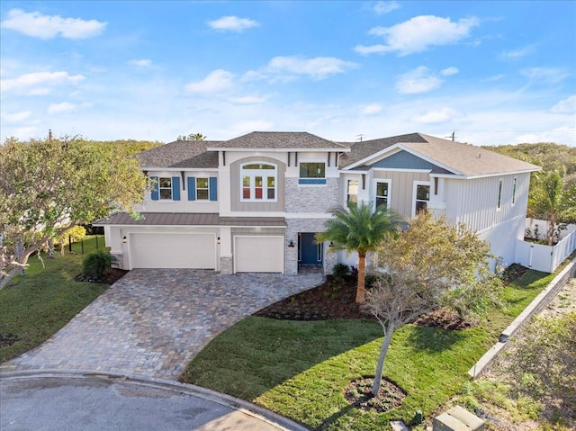 view of front of property with a garage, a standing seam roof, decorative driveway, and a front yard