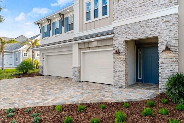 exterior space featuring a garage, stone siding, board and batten siding, and stucco siding