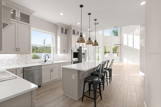 kitchen with stainless steel appliances, decorative backsplash, a sink, a kitchen island, and a kitchen breakfast bar