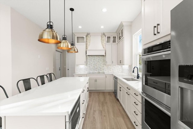 kitchen featuring stainless steel appliances, a kitchen island, a sink, tasteful backsplash, and custom range hood