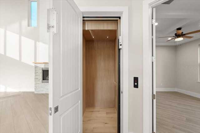 hallway featuring elevator, light wood-style flooring, baseboards, and recessed lighting