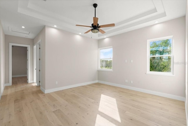 spare room with a tray ceiling, light wood-style flooring, baseboards, and recessed lighting