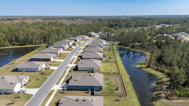 drone / aerial view featuring a residential view, a water view, and a view of trees