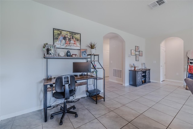 office space with light tile patterned floors, visible vents, and arched walkways