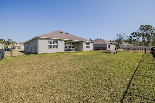 back of house featuring a fenced backyard, a lawn, and stucco siding