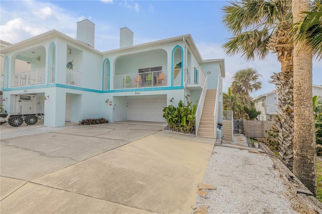 raised beach house featuring a balcony and a garage