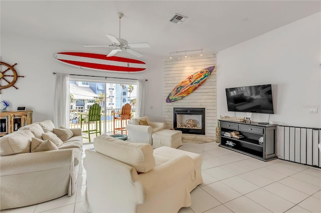 tiled living room featuring a fireplace, rail lighting, and ceiling fan
