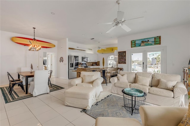 living room featuring ceiling fan with notable chandelier, sink, light tile patterned floors, and french doors
