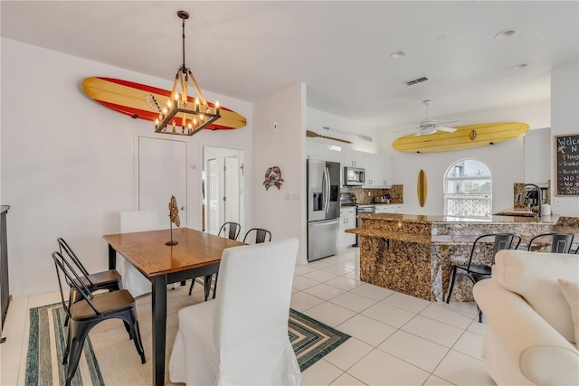dining area with ceiling fan with notable chandelier, sink, and light tile patterned floors