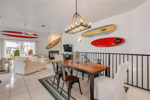 tiled dining room featuring ceiling fan with notable chandelier and a fireplace