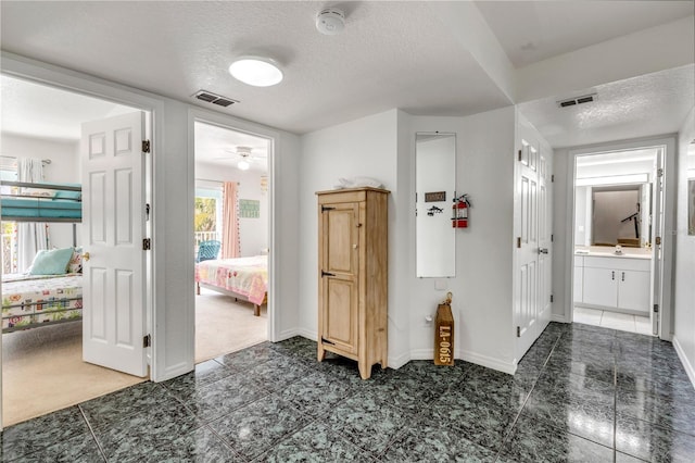 hall featuring dark colored carpet, sink, and a textured ceiling