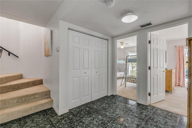 entrance foyer featuring dark carpet and a textured ceiling