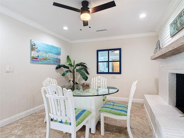 tiled dining room with a fireplace, ornamental molding, and ceiling fan