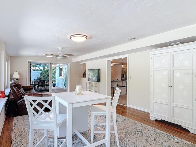 dining room with hardwood / wood-style floors, ceiling fan, and a textured ceiling