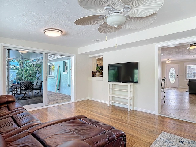 living room with wood-type flooring, ceiling fan, and a textured ceiling