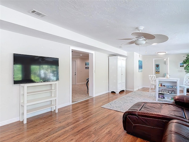 living room with hardwood / wood-style floors, ceiling fan, and a textured ceiling