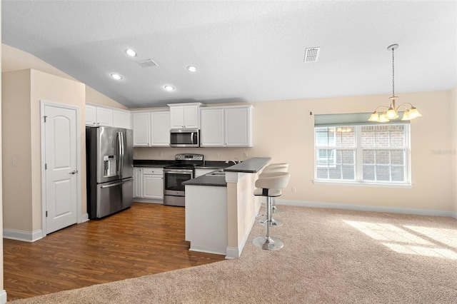 kitchen with lofted ceiling, a breakfast bar area, white cabinets, kitchen peninsula, and stainless steel appliances