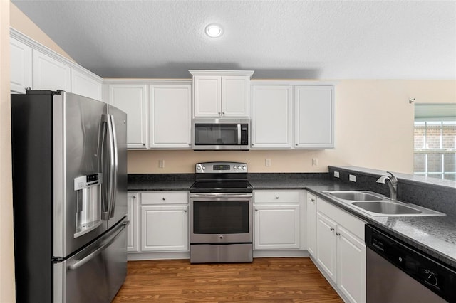 kitchen with sink, white cabinetry, a textured ceiling, appliances with stainless steel finishes, and dark hardwood / wood-style floors