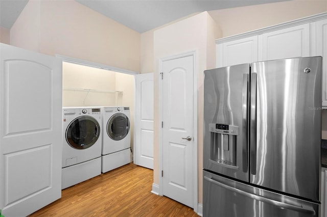 washroom with washing machine and clothes dryer and light wood-type flooring