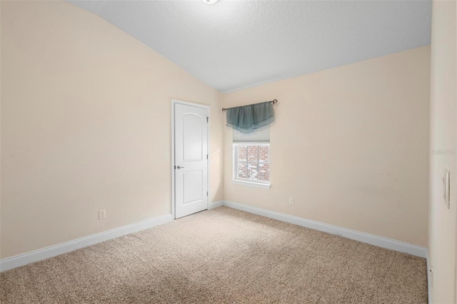 carpeted empty room featuring lofted ceiling and a textured ceiling