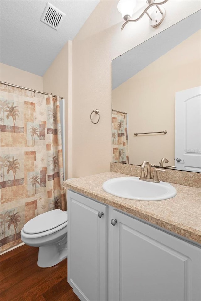 bathroom featuring hardwood / wood-style floors, vanity, a textured ceiling, vaulted ceiling, and toilet