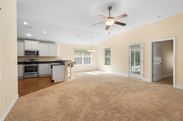 kitchen featuring carpet floors, white cabinetry, appliances with stainless steel finishes, and a breakfast bar