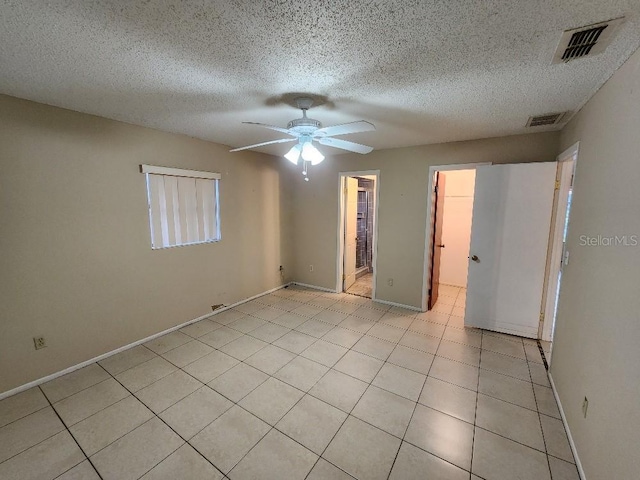 empty room featuring light tile patterned flooring, ceiling fan, and a textured ceiling