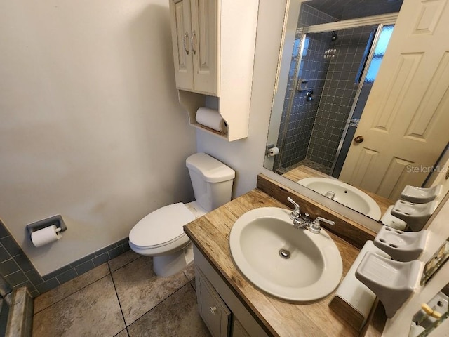 bathroom with a tile shower, vanity, tile patterned floors, and toilet