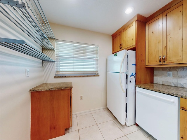 kitchen with light tile patterned floors, white appliances, baseboards, decorative backsplash, and brown cabinets