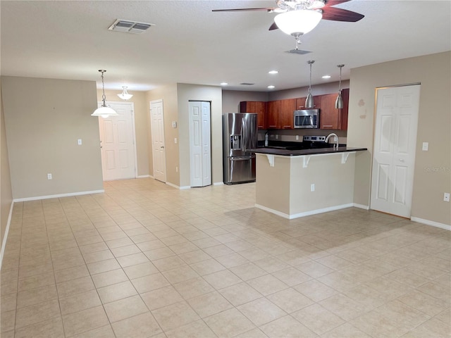 kitchen with dark countertops, a peninsula, stainless steel appliances, a kitchen bar, and recessed lighting