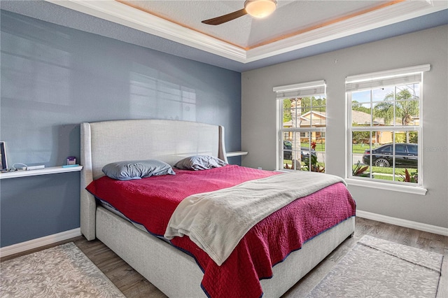 bedroom with multiple windows, baseboards, and wood finished floors