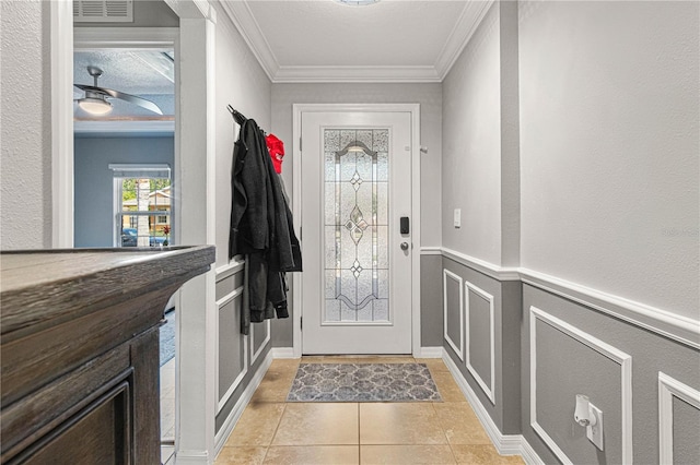 doorway with light tile patterned flooring, a decorative wall, a wainscoted wall, visible vents, and ornamental molding