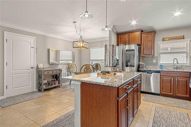 kitchen featuring light stone counters, crown molding, stainless steel appliances, a sink, and a kitchen island