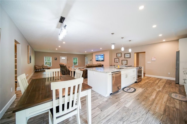 kitchen with stainless steel dishwasher, hanging light fixtures, light stone counters, and a center island