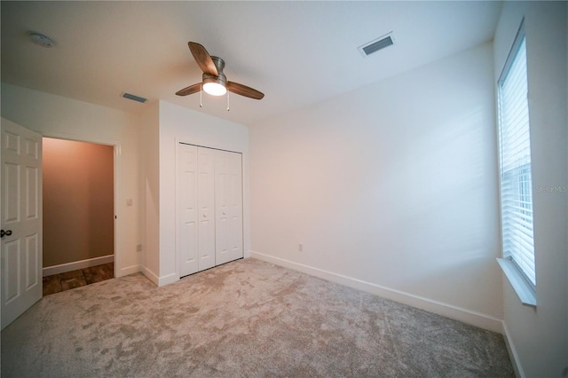 unfurnished bedroom with a closet, light colored carpet, and ceiling fan